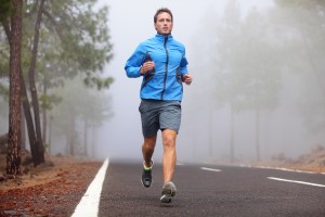 Healthy running runner man workout on mountain road. Jogging male fitness model working out training for marathon on forest road in amazing nature landscape.